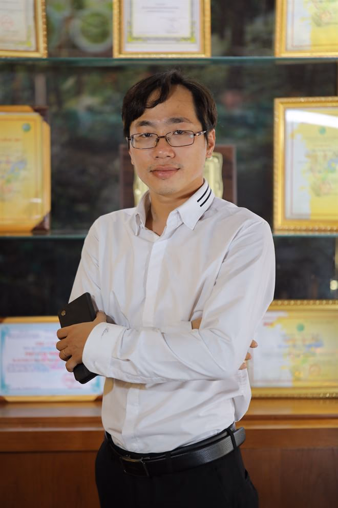 Nguyễn Tự Tin đứng trước bức tường treo kín bằng khen và giấy chứng nhận của Phở ’S.
